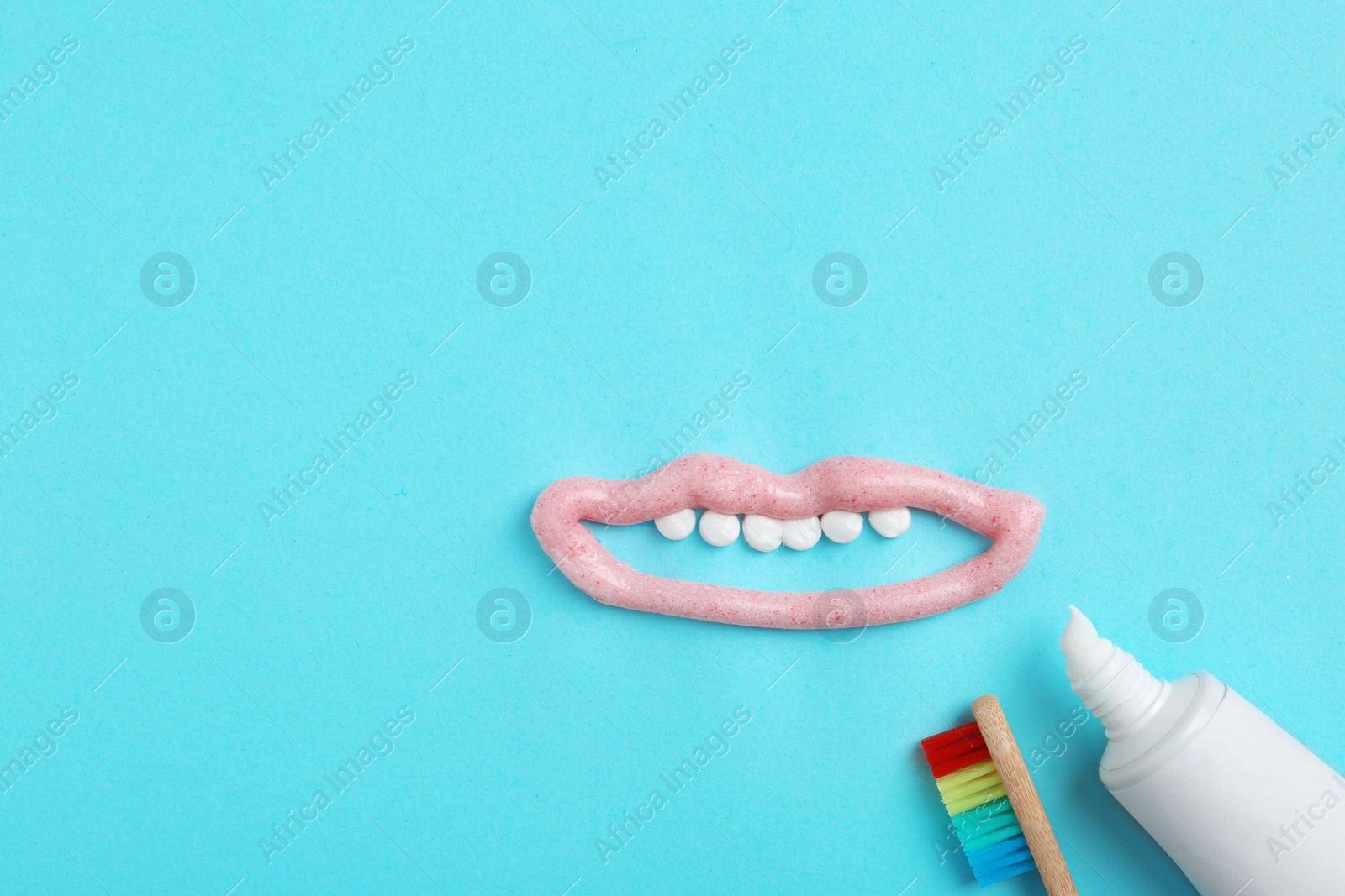 Photo of Mouth with teeth made of paste, tube and brush on color background, flat lay. Space for text