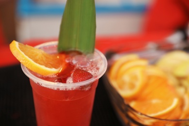 Photo of Delicious refreshing drink in plastic cup on bar counter, closeup