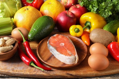 Photo of Healthy meal. Different vegetables and raw salmon on wooden table