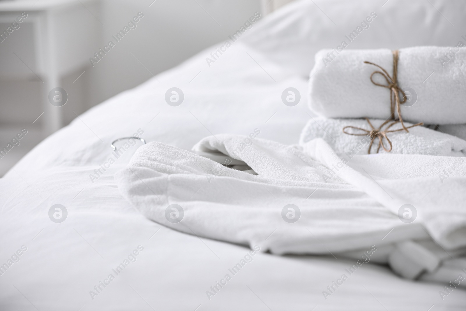 Photo of Clean soft bathrobe and towels on bed