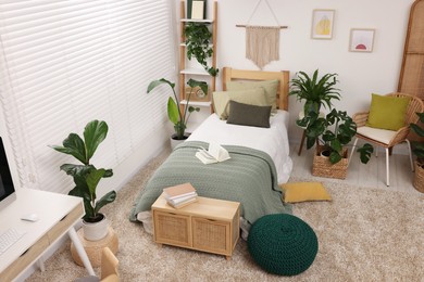 Photo of Large comfortable bed and potted houseplants in stylish bedroom. Interior design