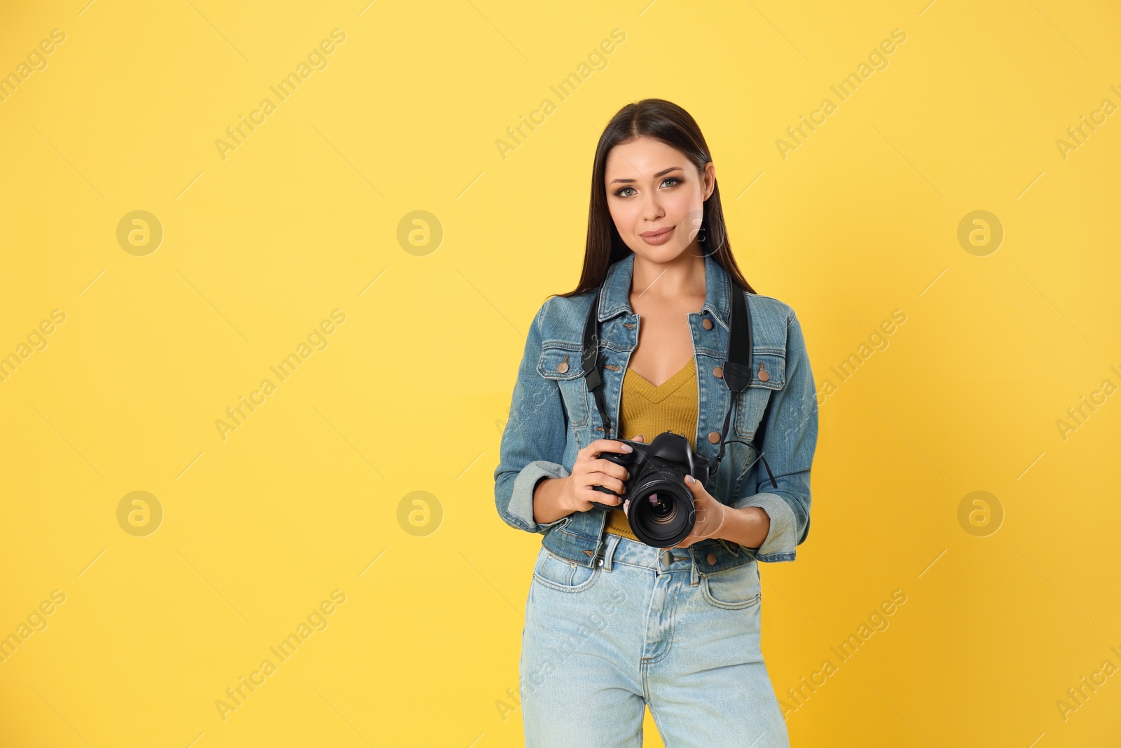 Photo of Professional photographer working on yellow background in studio. Space for text