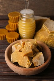 Photo of Different natural beeswax blocks and honey on wooden table