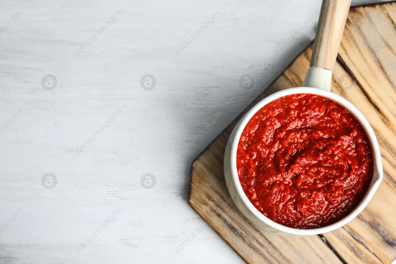 Photo of Delicious tomato sauce in pan on white wooden table, top view. Space for text