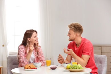 Photo of Happy young couple having breakfast at table in room