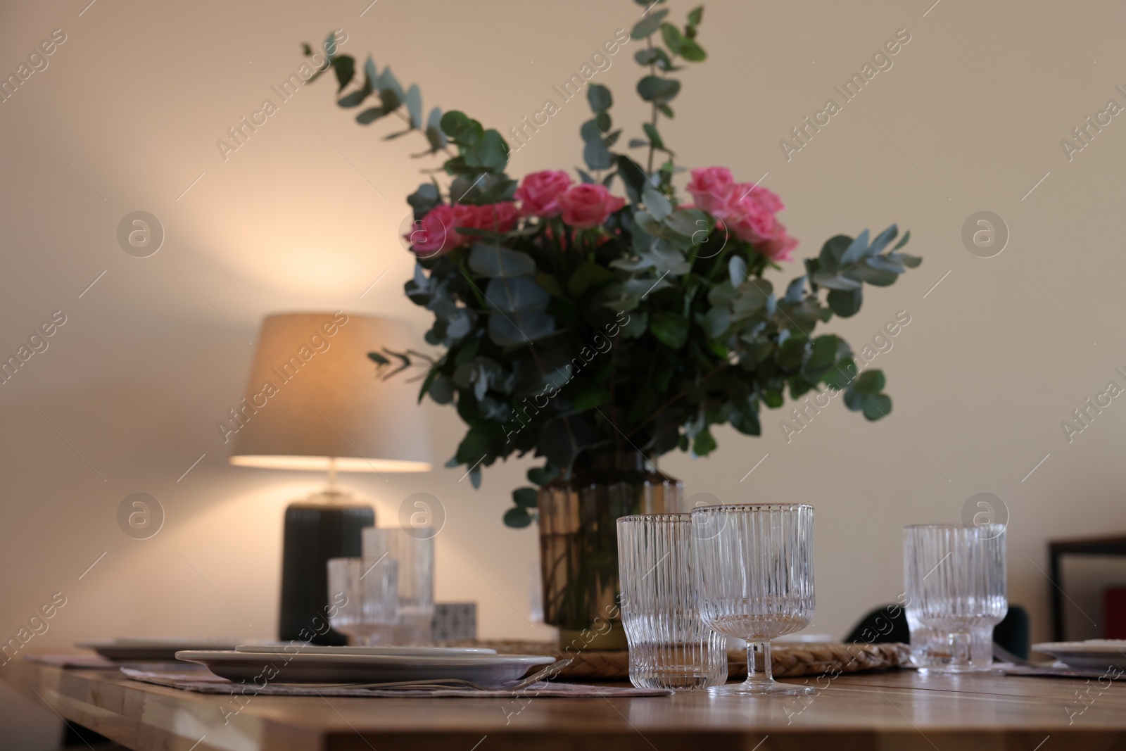 Photo of Beautiful table setting with bouquet indoors. Roses and eucalyptus branches in vase