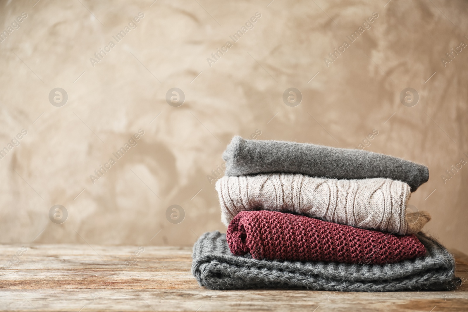 Photo of Stack of warm knitted clothes on table