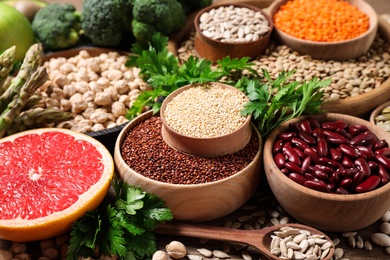 Photo of Fresh vegetables, grapefruit and seeds on wooden table, closeup