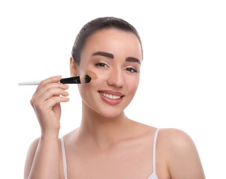 Woman applying foundation on face with brush against white background