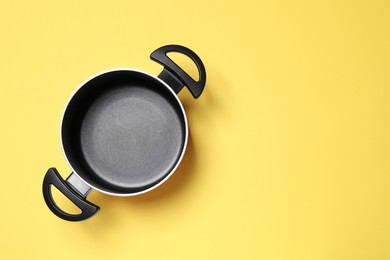 Photo of Empty pot on yellow background, top view. Space for text