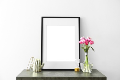 Photo of Mockup of blank frame and flowers on table