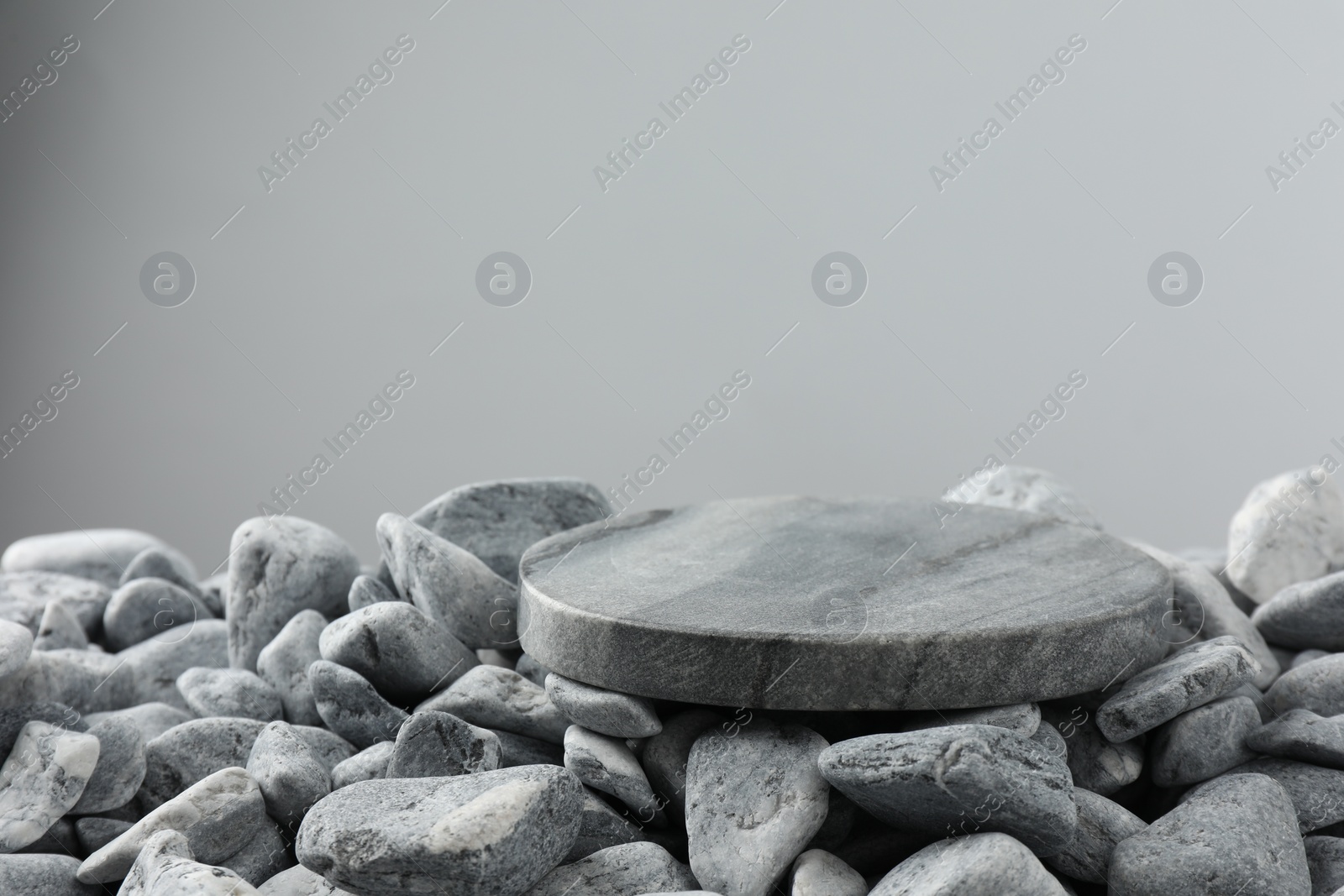 Photo of Presentation for product. Stone and pebbles on grey background. Space for text