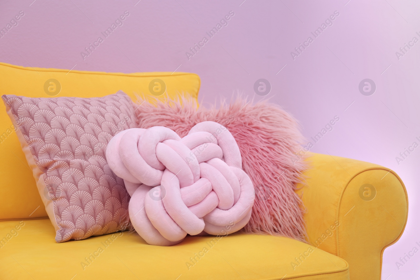 Photo of Sofa with different soft pillows on color background. Interior element