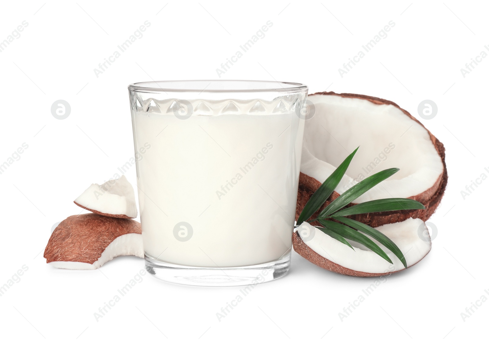 Photo of Glass of delicious vegan milk, coconut pieces and green leaf on white background