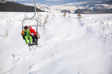 People using chairlift at mountain ski resort, space for text. Winter vacation