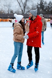 Happy young couple skating at outdoor ice rink