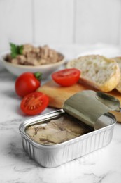 Photo of Open tin can of tasty cod liver on white marble table