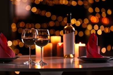 Photo of Romantic table setting with glasses of wine and burning candles against blurred background