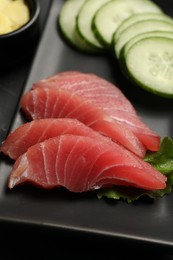 Tasty sashimi (pieces of fresh raw tuna) on black plate, closeup