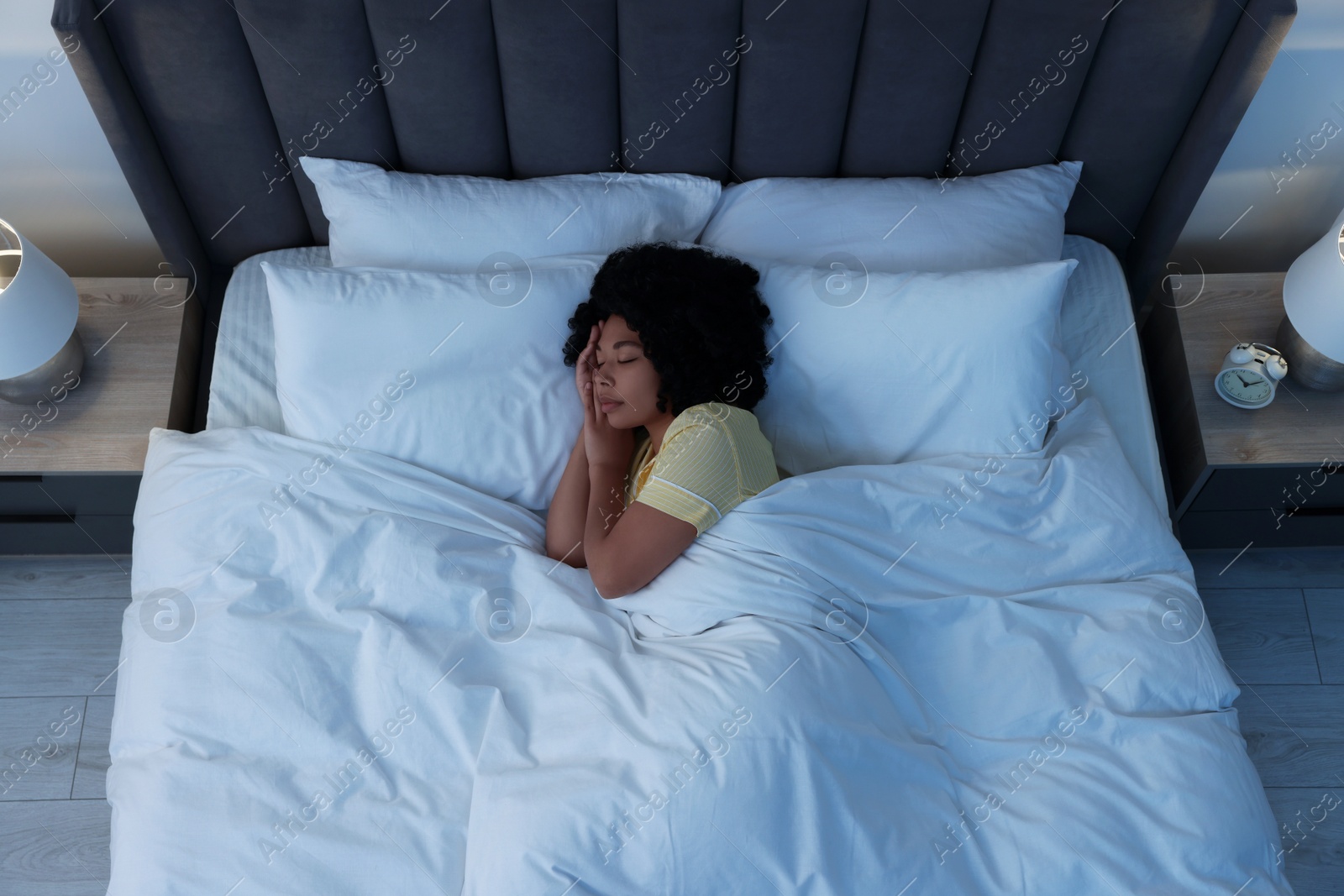 Photo of Young woman sleeping in soft bed at night, above view