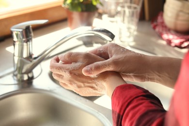 Photo of Woman washing hands in kitchen, closeup view