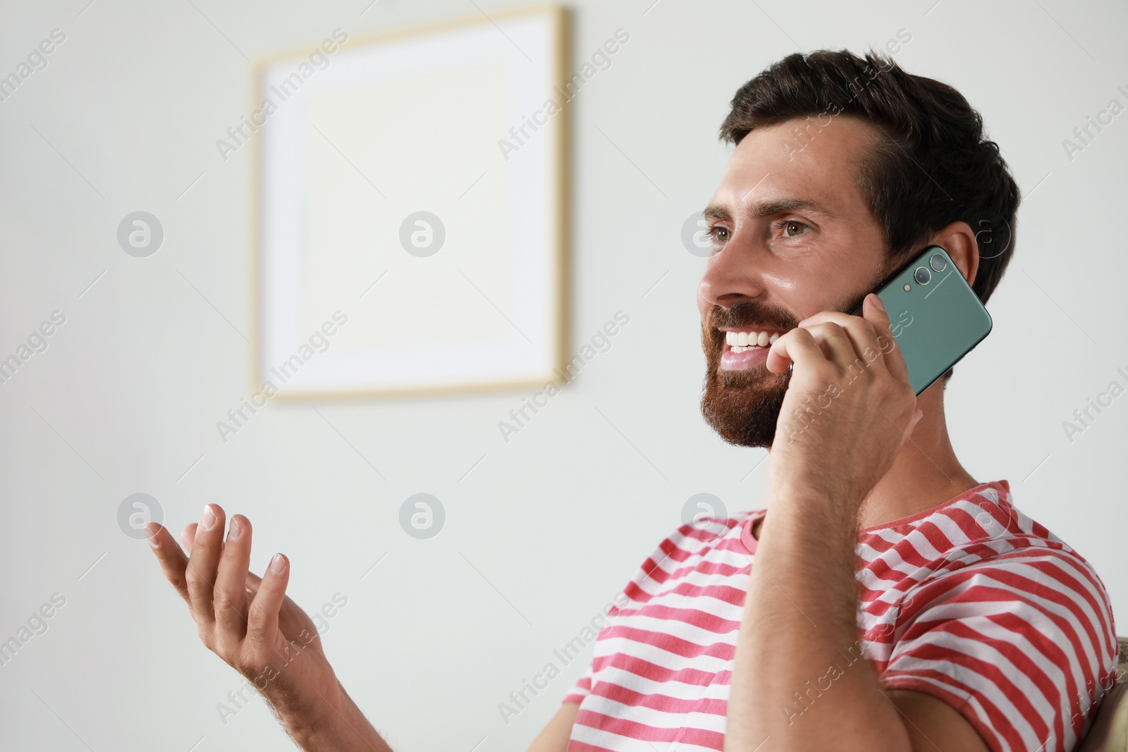 Photo of Handsome man talking on phone at home, space for text