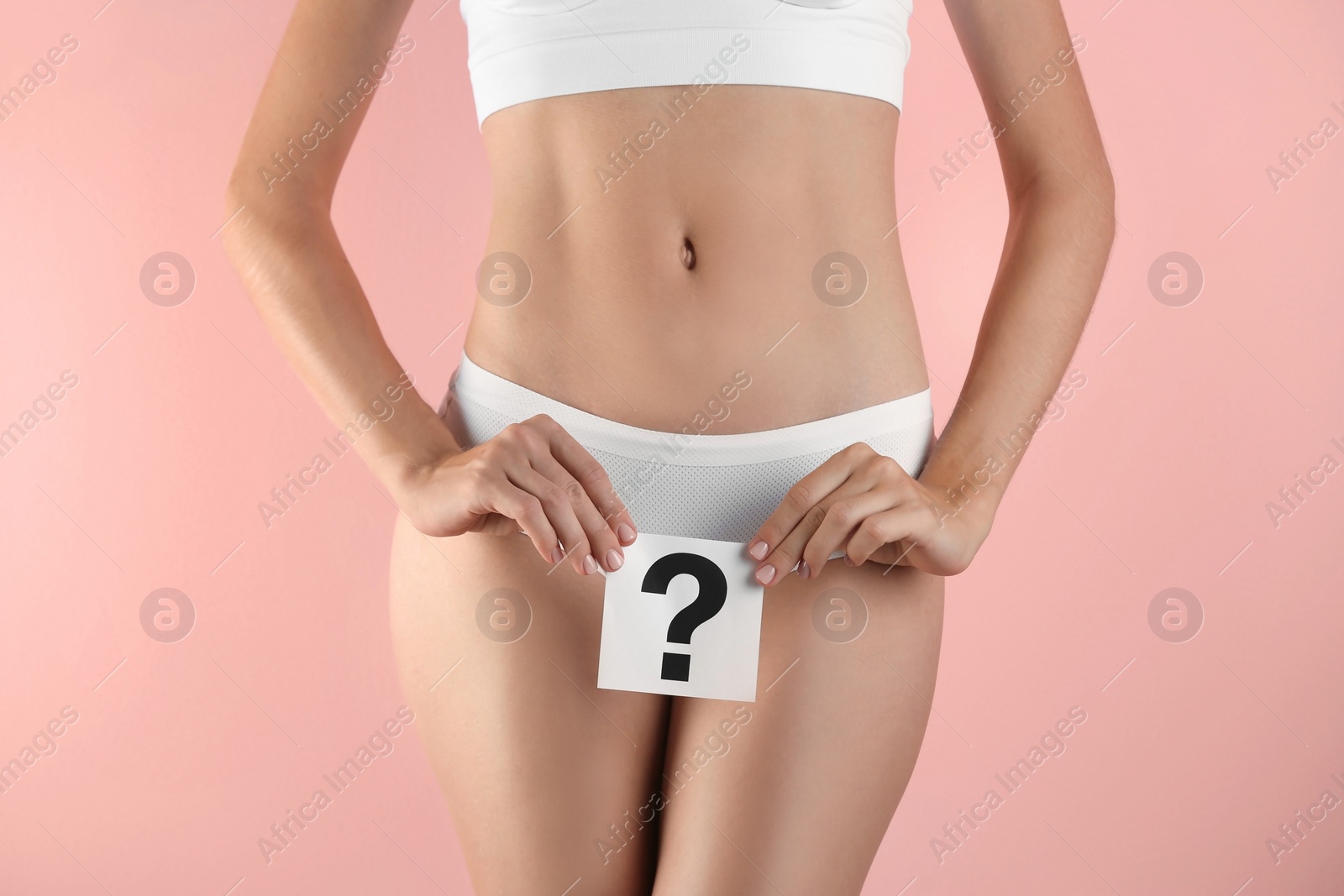 Photo of Young woman holding card with question mark on color background. Gynecology concept
