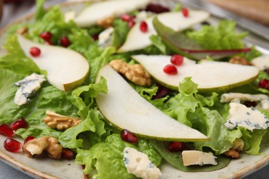 Photo of Delicious pear salad with pomegranate, walnuts and blue cheese on plate, closeup