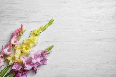 Photo of Flat lay composition with beautiful gladiolus flowers on wooden background