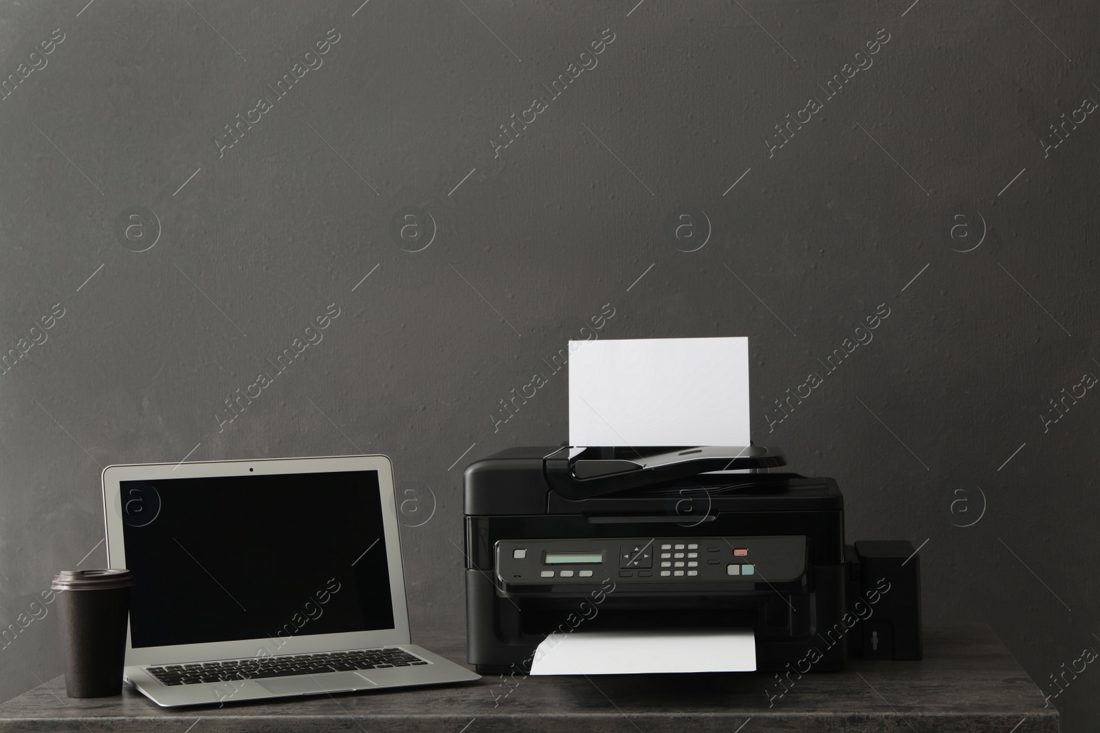 Photo of Modern printer with paper and laptop on grey table