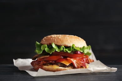 Tasty burger with bacon on wooden table