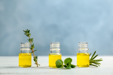 Bottles with essential oils and fresh herbs on table