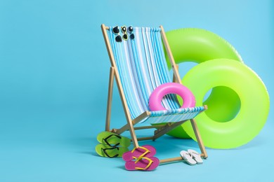 Deck chair and beach accessories on light blue background