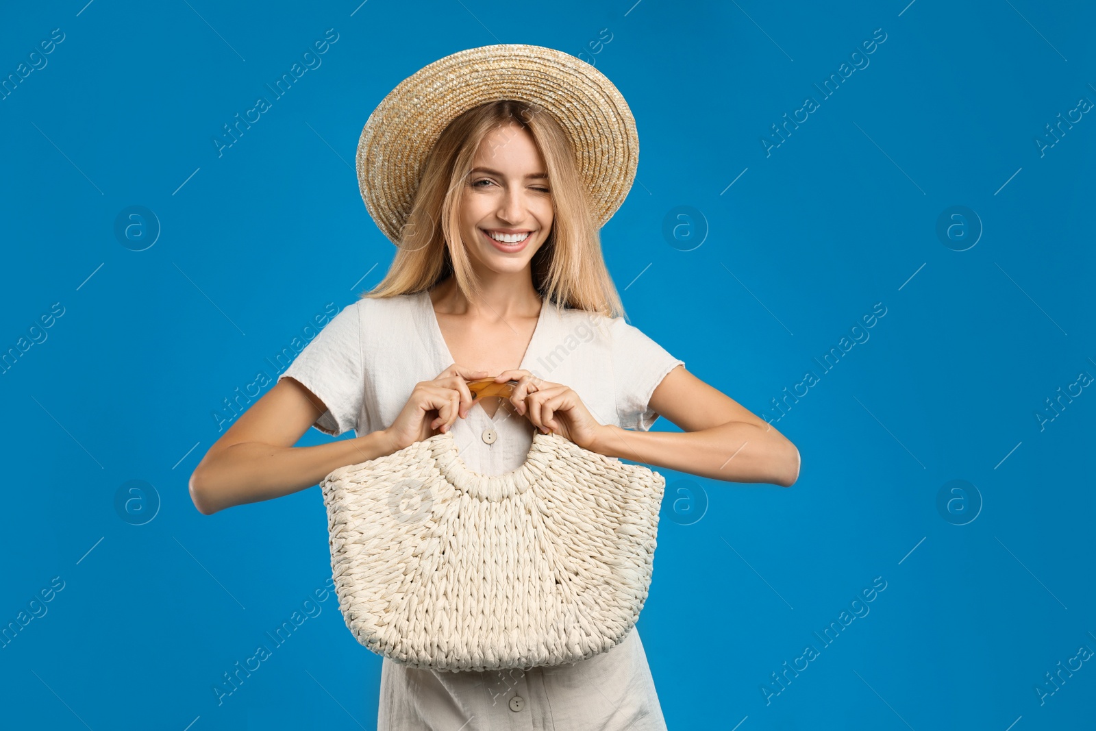 Photo of Beautiful young woman with stylish straw bag on blue background