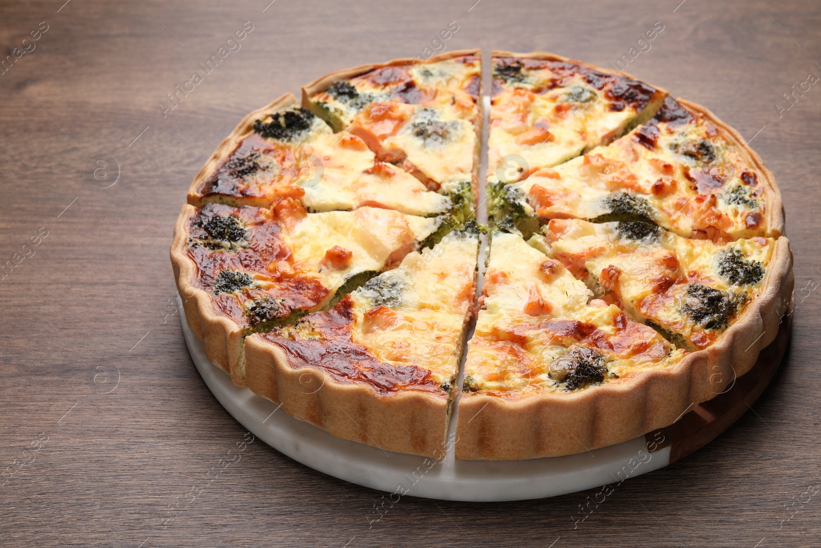 Photo of Delicious homemade quiche with salmon and broccoli on wooden table