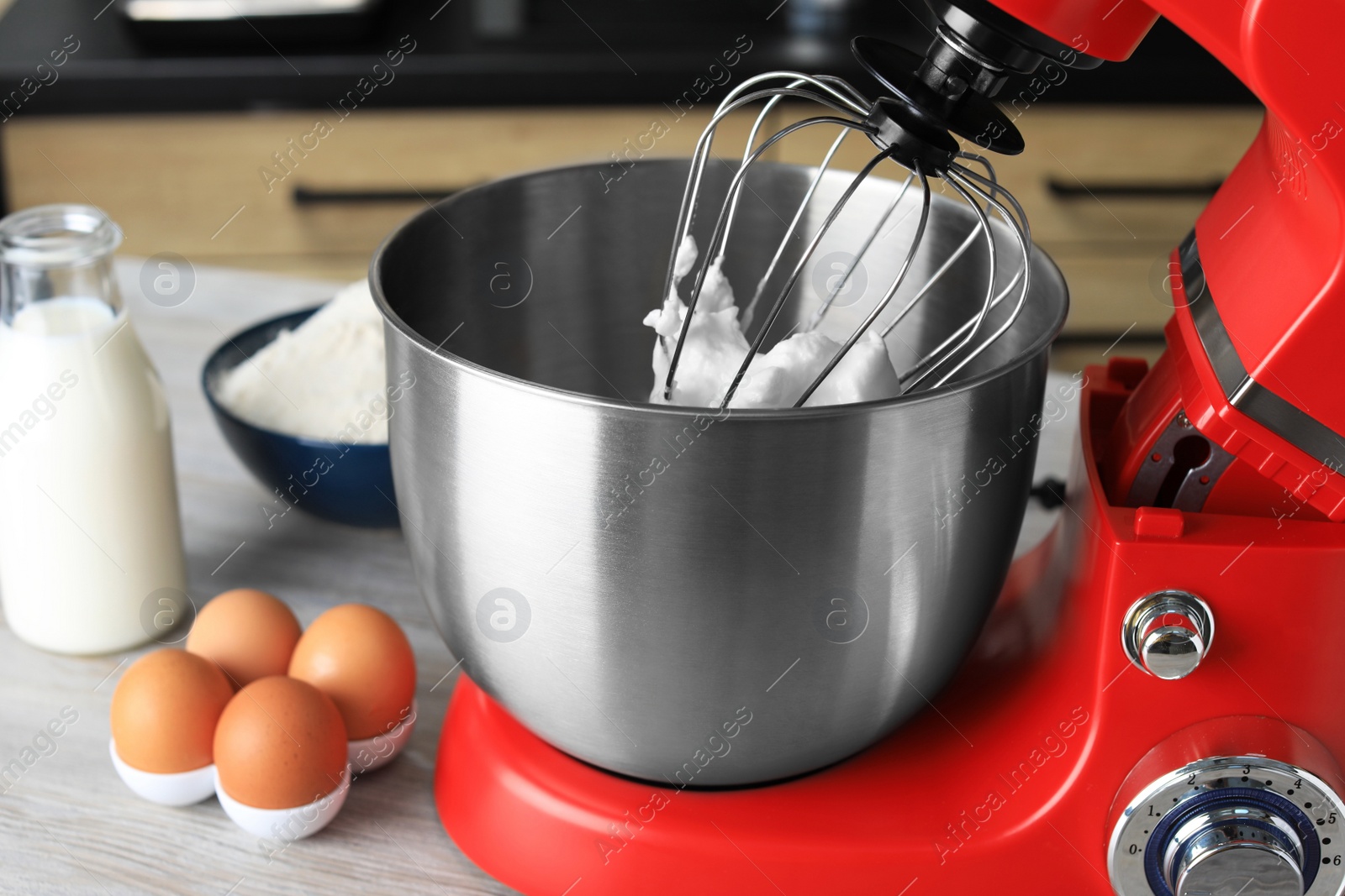 Photo of Modern stand mixer and ingredients on wooden table in kitchen, closeup. Home appliance