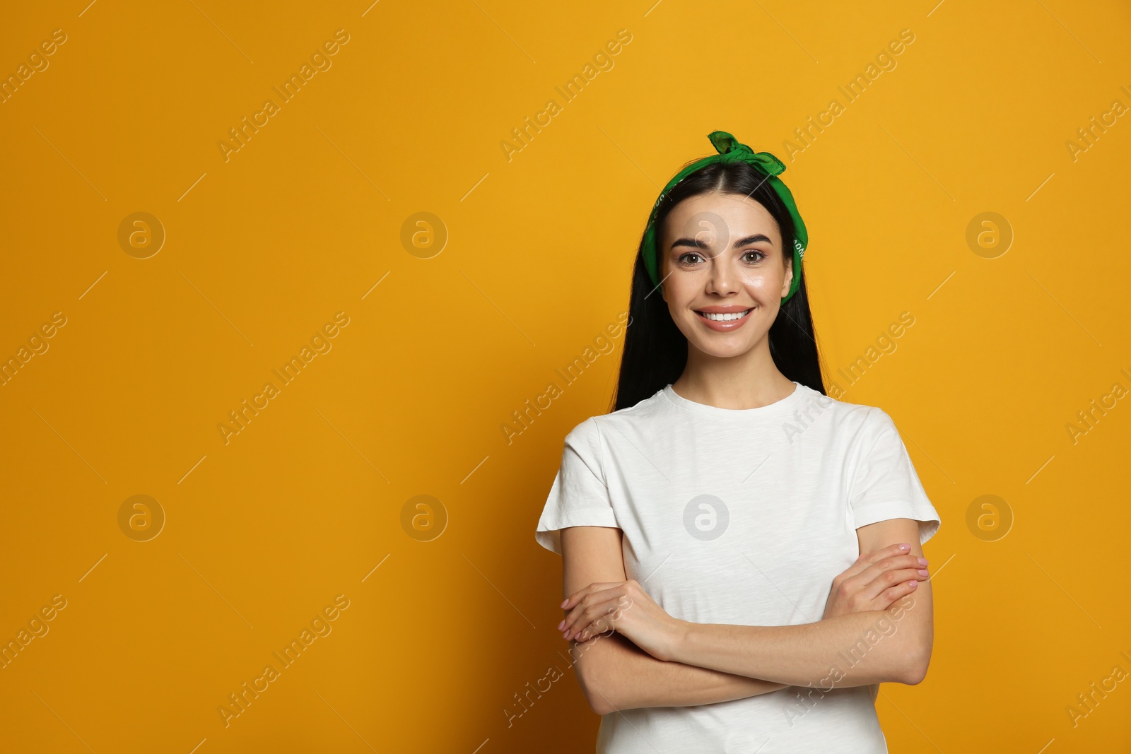 Photo of Young woman wearing stylish bandana on orange background, space for text