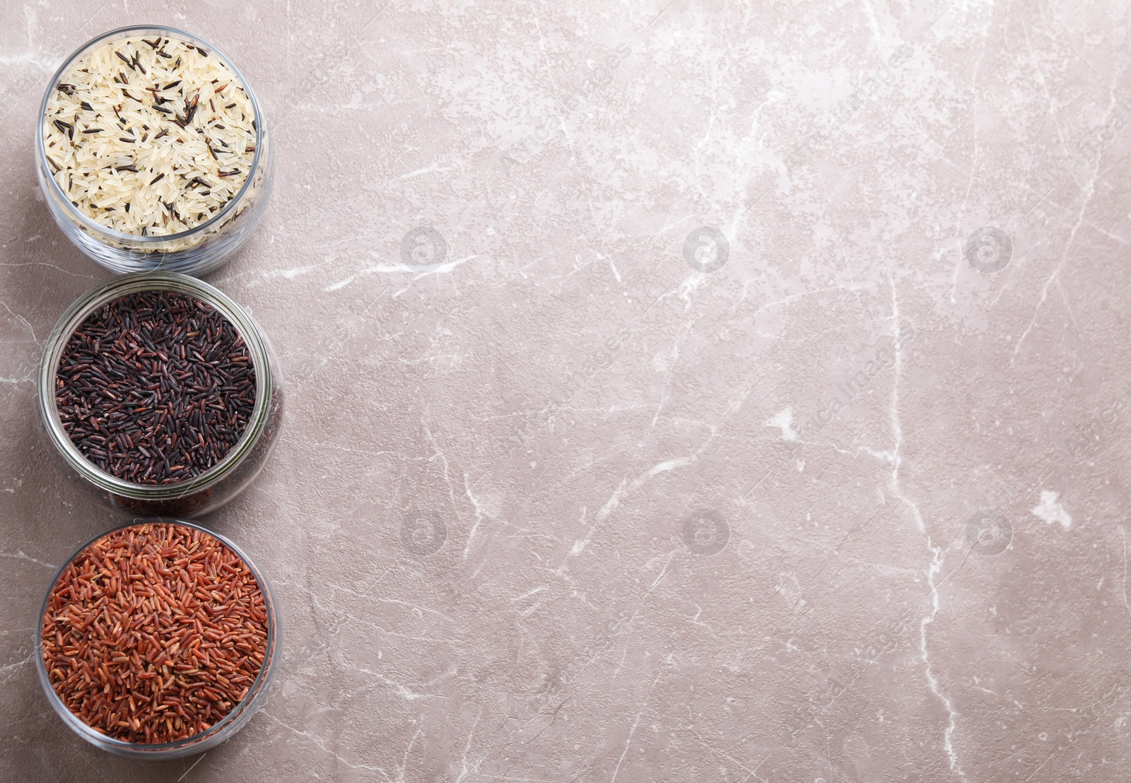 Photo of Brown and polished rice grey on marble table, flat lay. Space for text