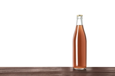 Photo of Bottle of delicious kvass on wooden table against white background