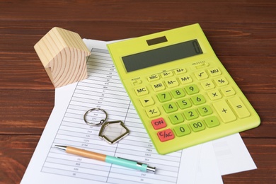 Photo of Calculator, house model and documents on wooden table. Real estate agent's workplace