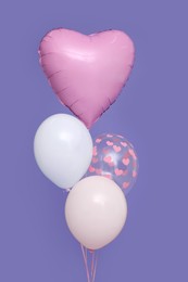 Photo of Bunch of heart and round shaped balloons for birthday party on violet background