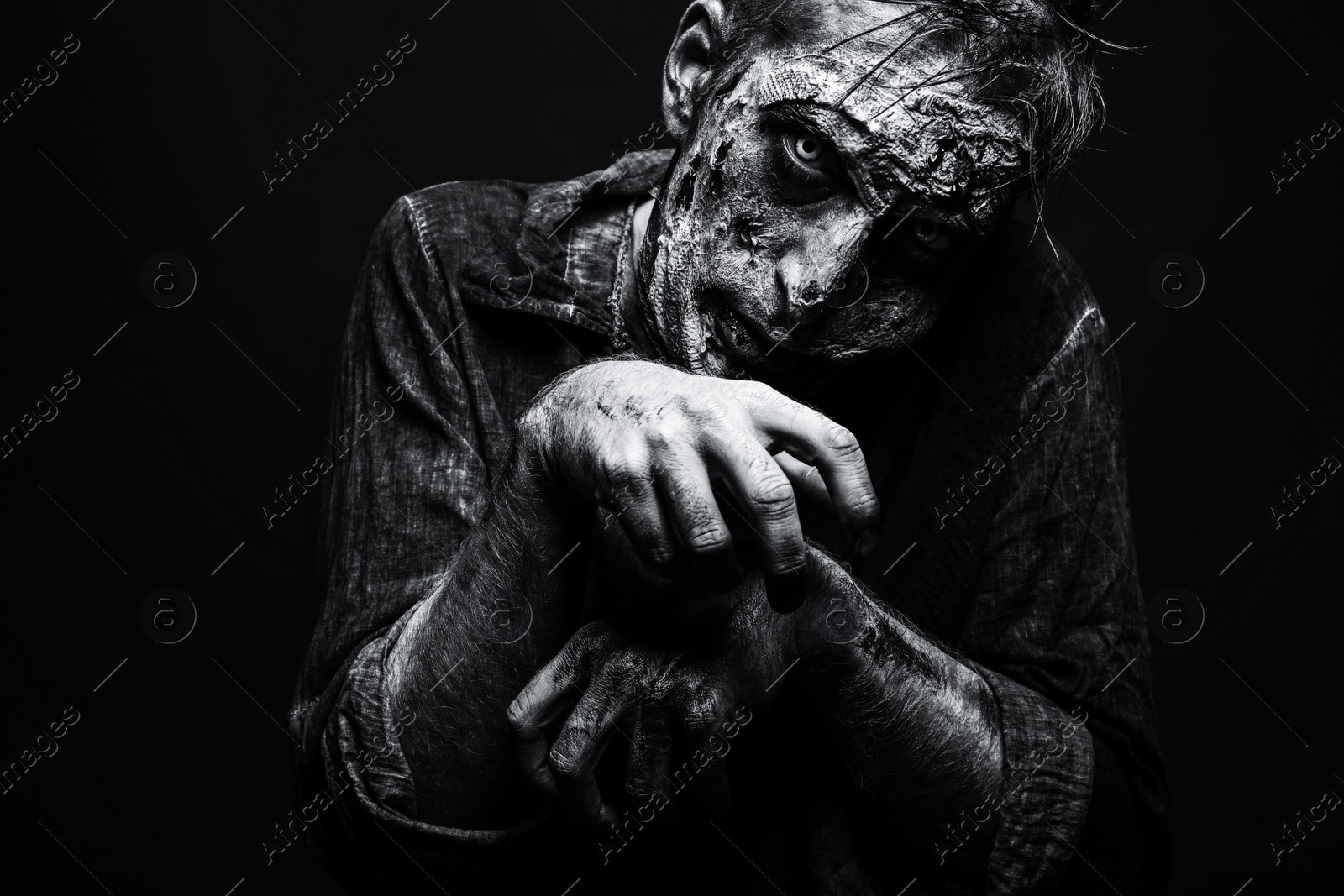 Photo of Scary zombie on dark background, black and white effect. Halloween monster