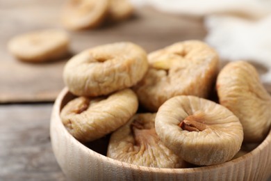 Photo of Tasty dried figs in bowl on wooden table, closeup