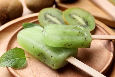 Photo of Plate of tasty kiwi ice pops on table, closeup. Fruit popsicle