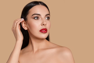 Photo of Portrait of young woman wearing beautiful red lipstick on beige background