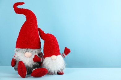 Photo of Two cute Christmas gnomes on light blue background. Space for text