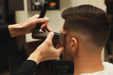 Photo of Professional hairdresser making stylish haircut in salon, closeup