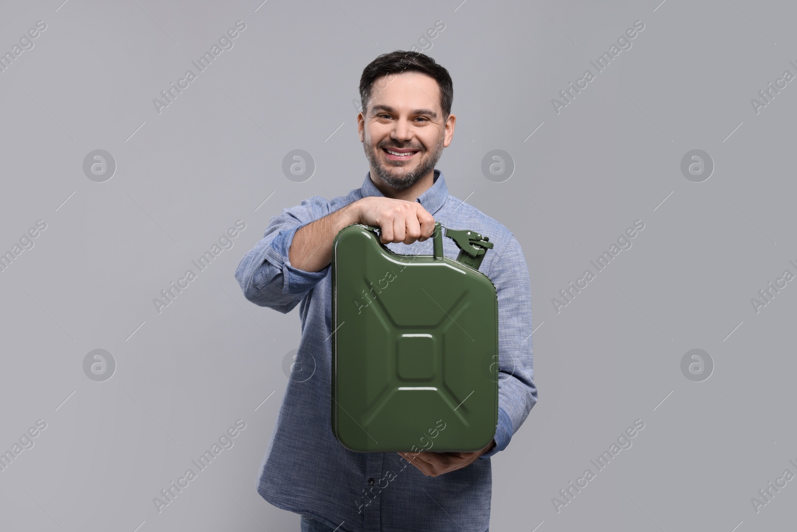 Photo of Man holding khaki metal canister on light grey background