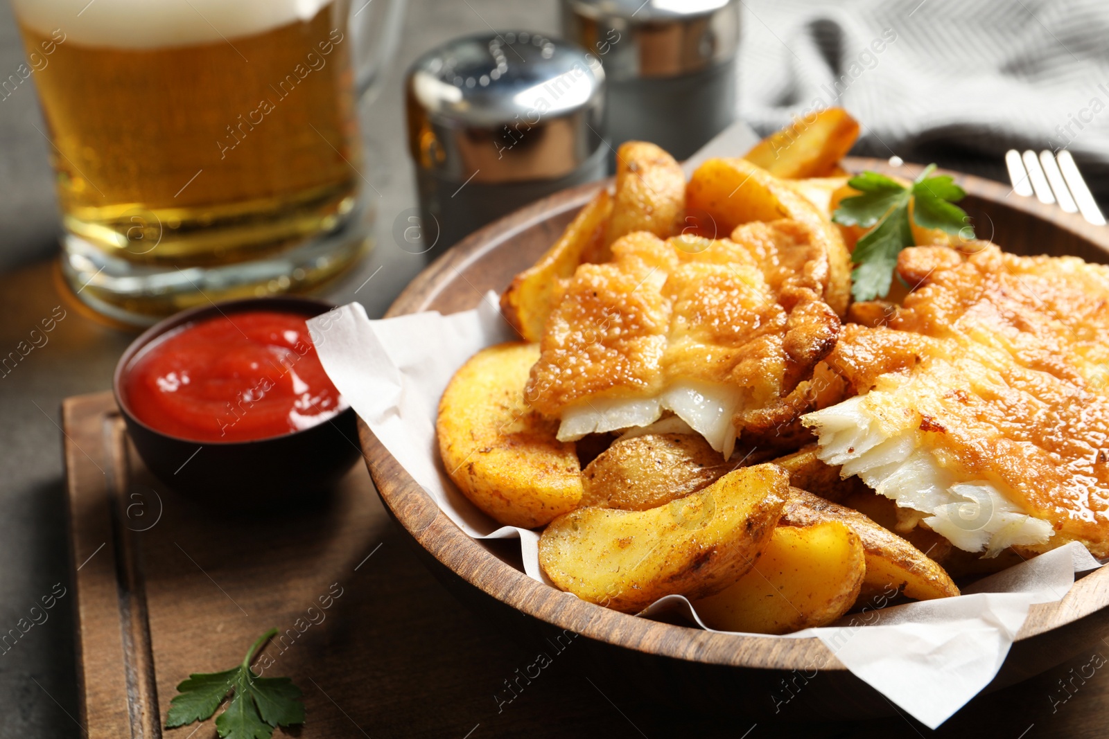 Photo of Wooden plate with British traditional fish and potato chips on table. Space for text