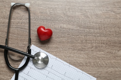 Photo of Cardiogram report, stethoscope and red decorative heart on wooden background, flat lay with space for text